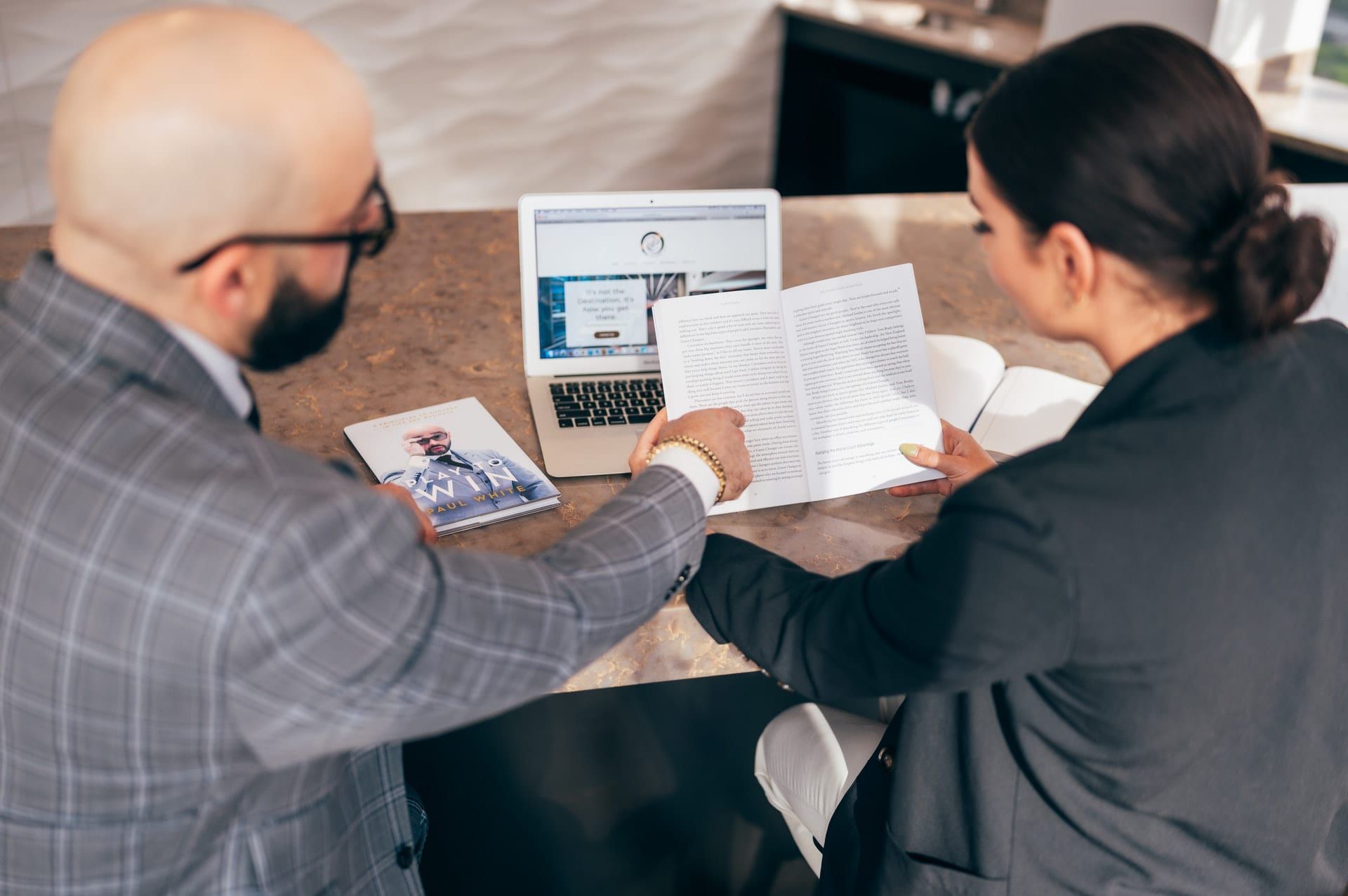 Two people going through a printed report beside a laptop