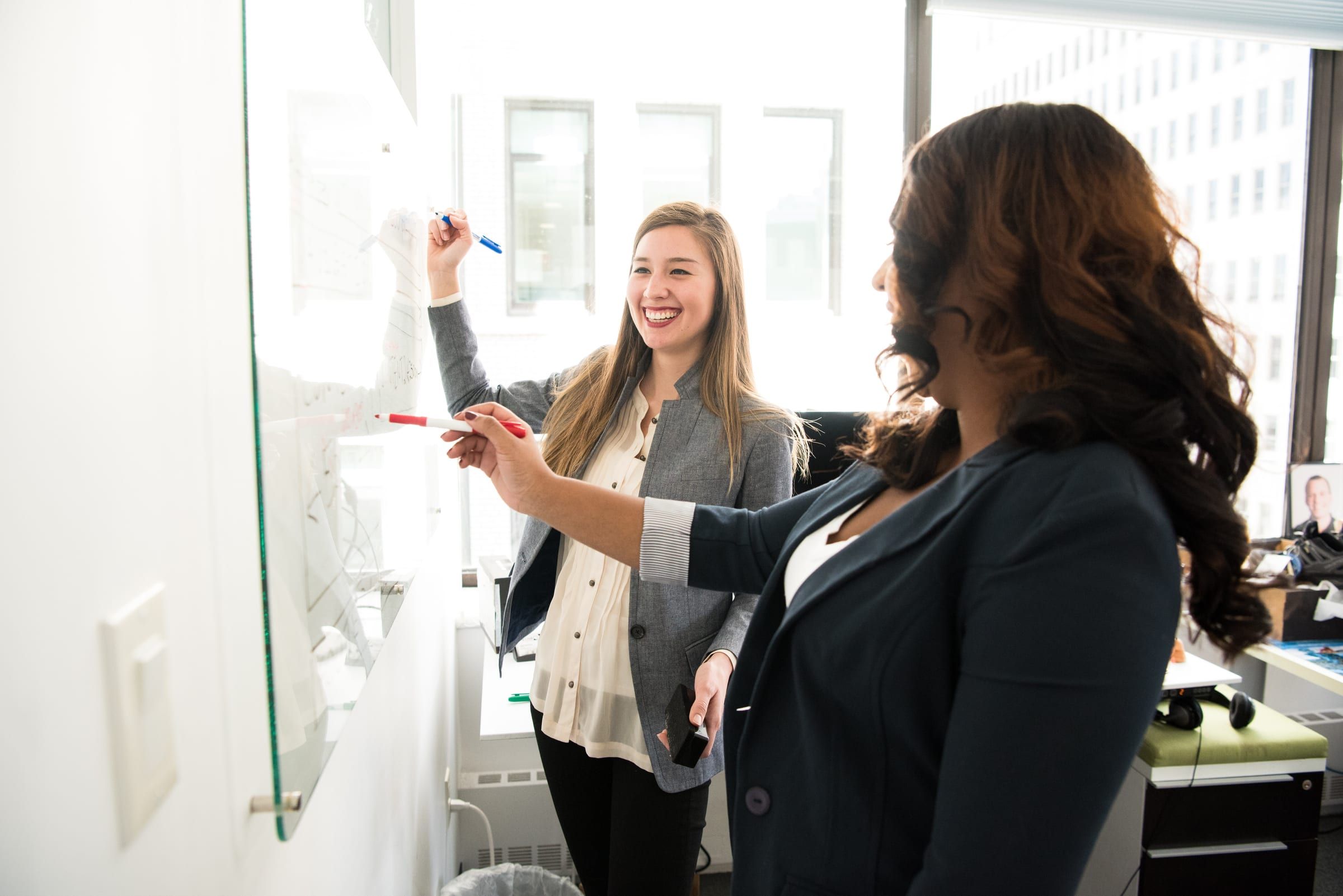 Two women working at a whiteboard