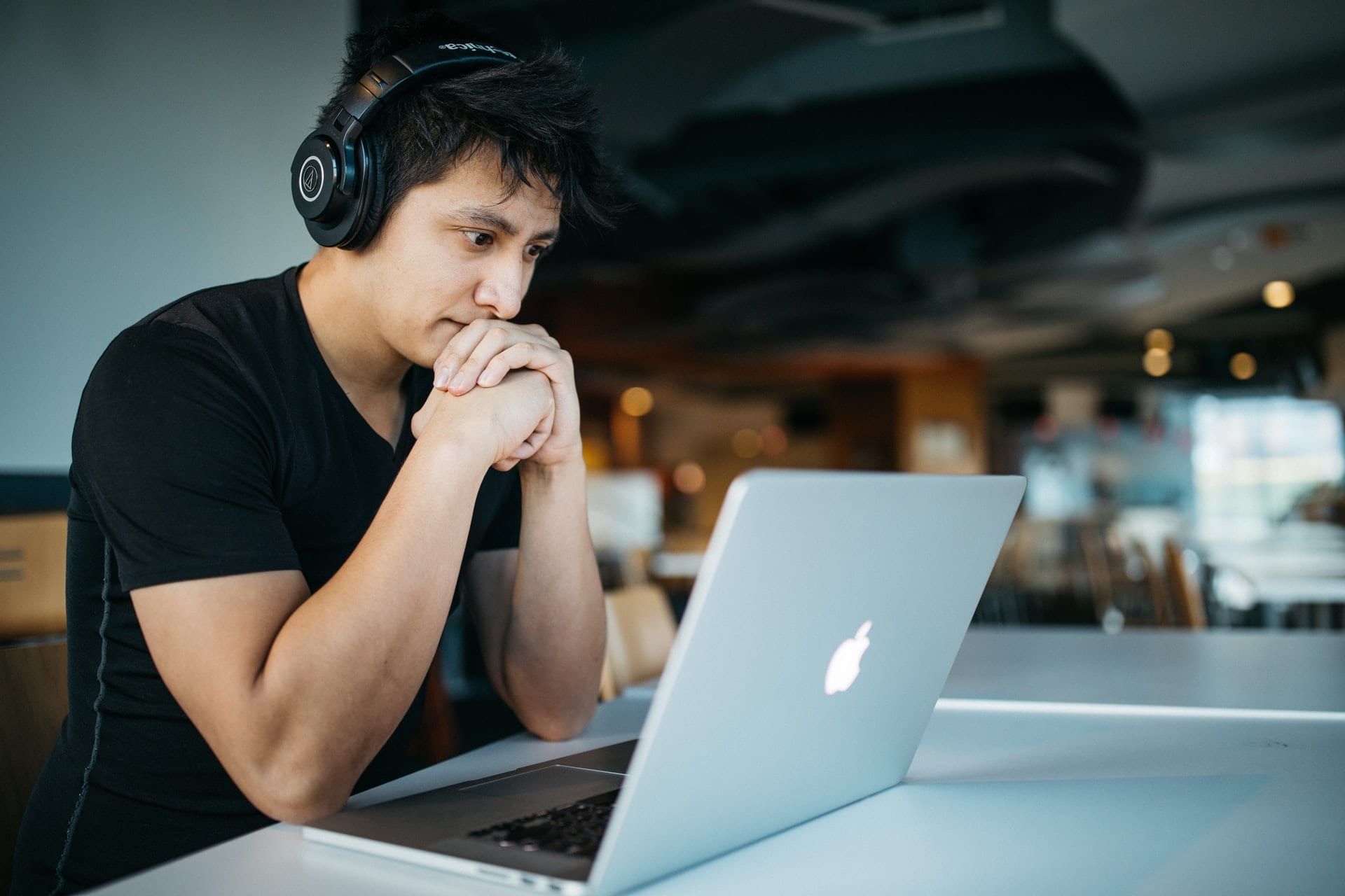 A man with headphones looking at the screen of a laptop
